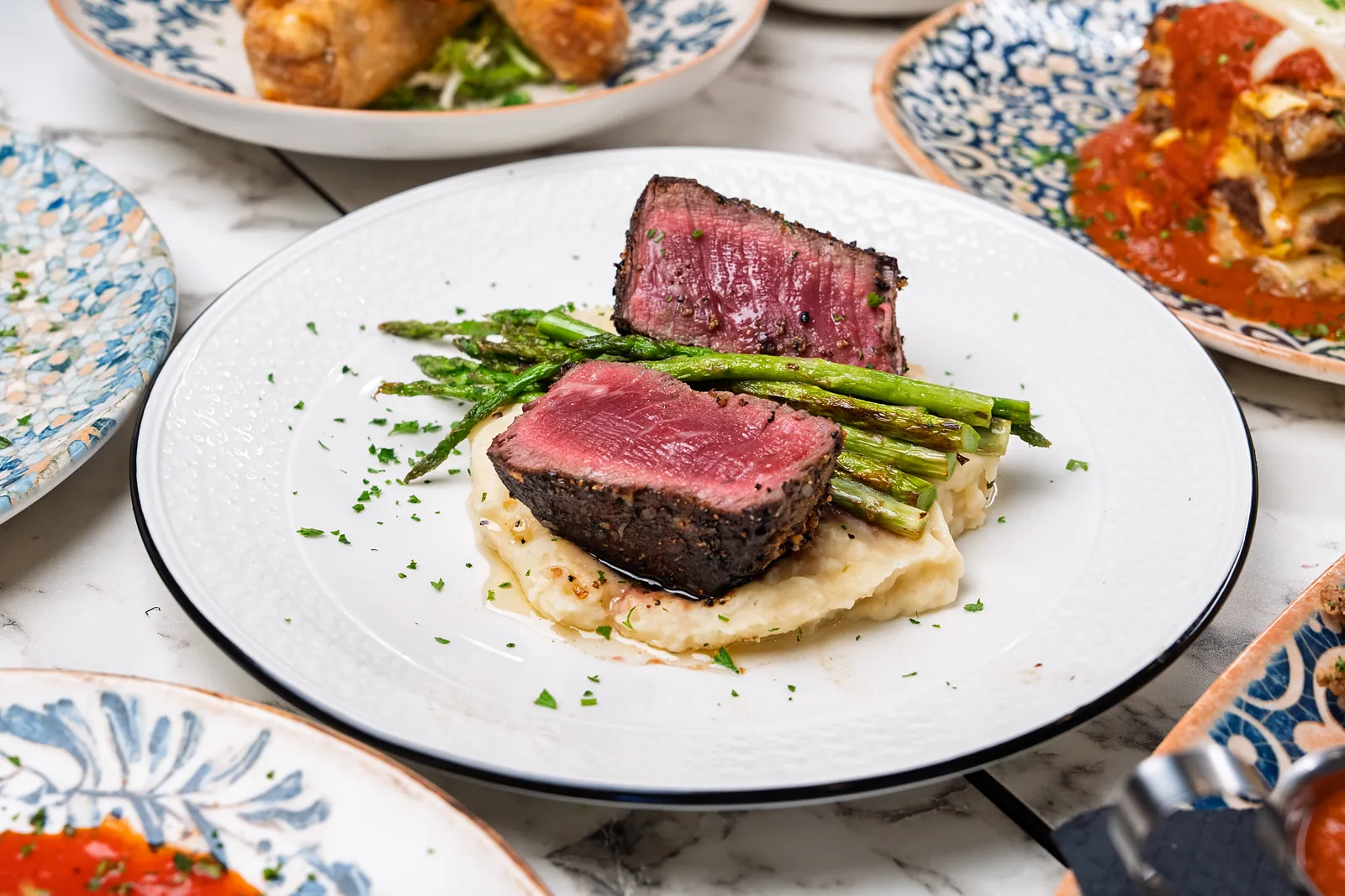 Seared filet cut to show a rare centre, with grilled asparagus on mashed potato